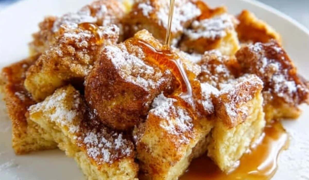 French Toast Casserole topped with maple syrup and powdered sugar