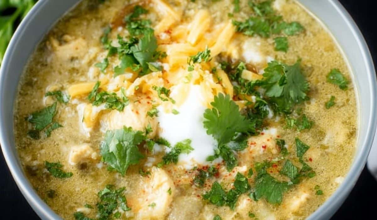Green Enchilada Chicken Soup in a white bowl topped with cilantro and cheese
