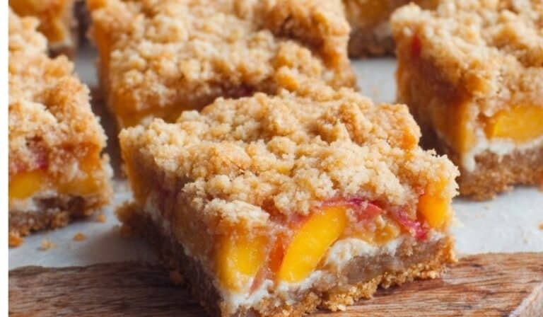 Close-up of freshly baked peaches and cream crumble bars with golden buttery topping on a wooden board