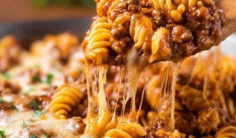 Beef Enchilada Pasta with melted cheese being scooped from skillet