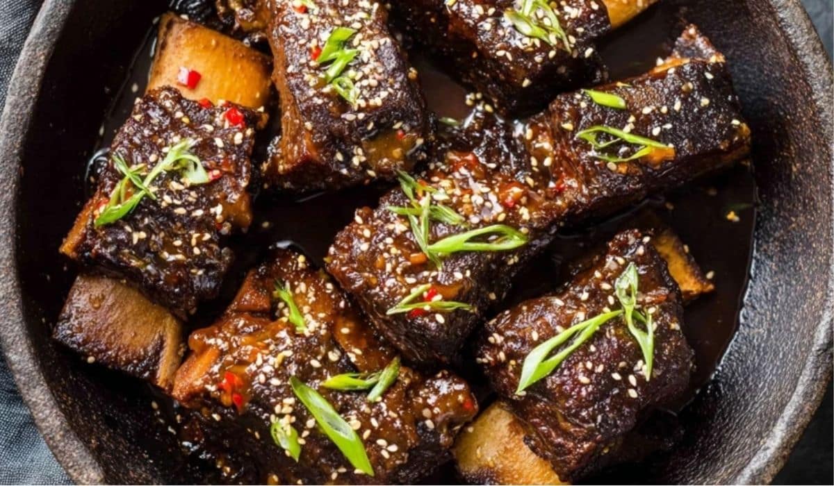 Easy Korean Slow Cooker Short Ribs served in a skillet with sesame seeds and green onions