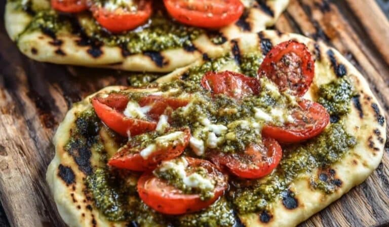 Grilled flatbread with pesto and tomatoes topped with fresh basil and melted cheese