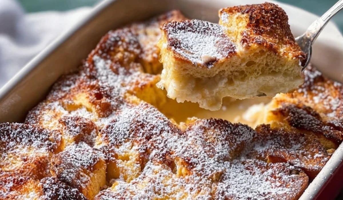 Overnight Eggnog-French Toast Casserole in a baking dish topped with golden crust and powdered sugar