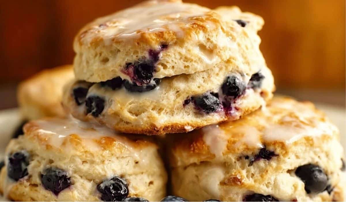 Blueberry Biscuits stacked with glaze and fresh blueberries on a plate