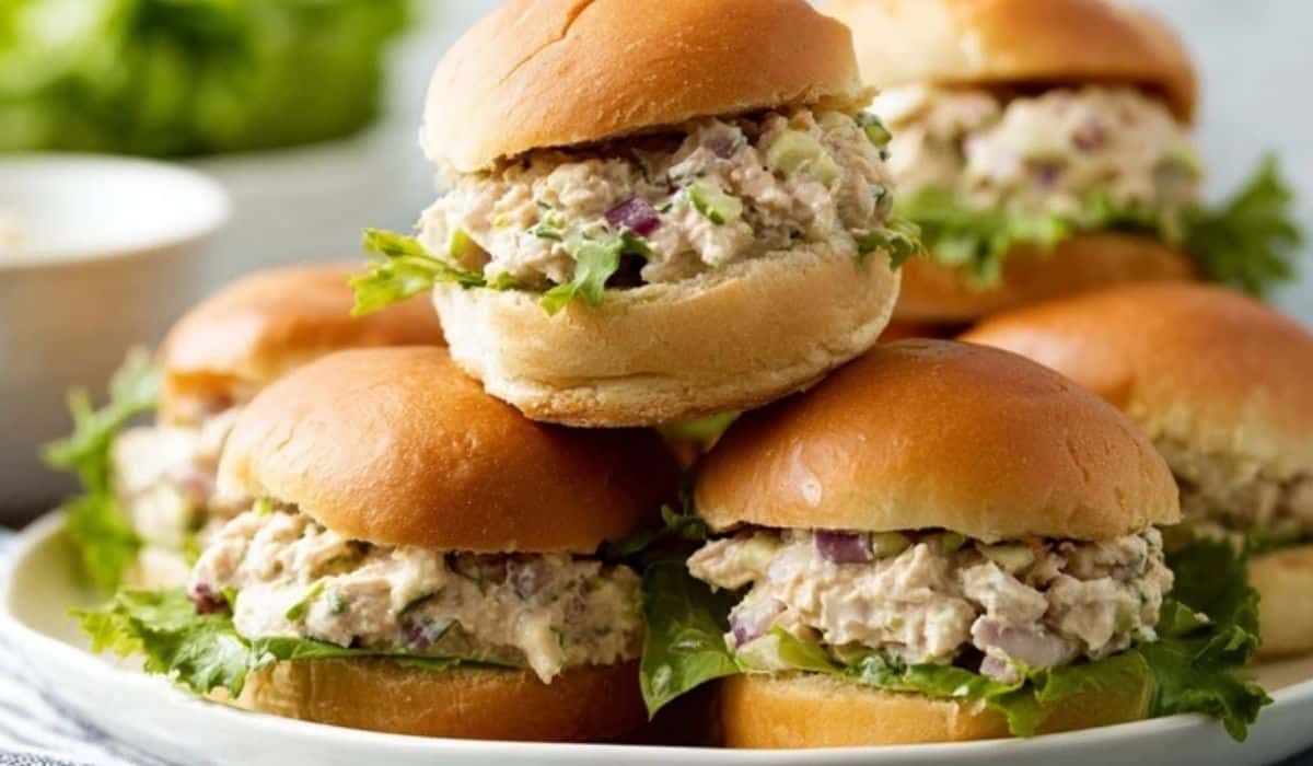 Hummus Chicken Salad Sliders stacked on a white plate with lettuce and onions, showing creamy, savory filling