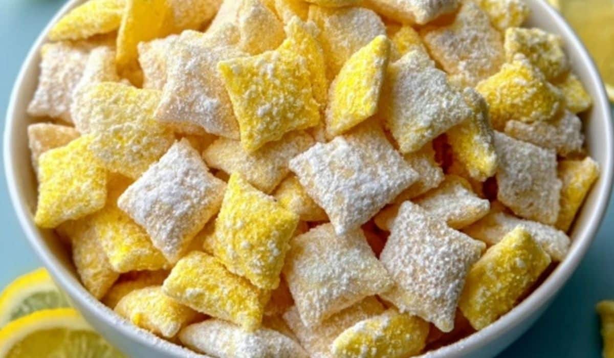 Zesty Lemonade Puppy Chow Snack Recipe in a white bowl dusted with powdered sugar