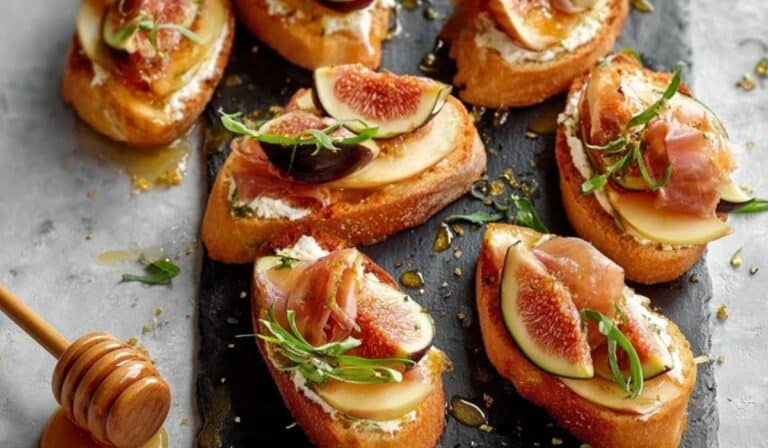 Brie, Apple, and Fig Crostini Appetizer served on slate board with honey drizzle