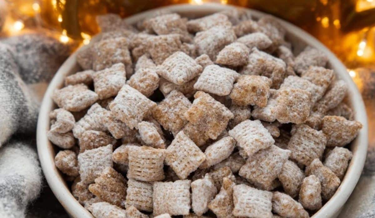 Bowl of Peanut Butter Puppy Chow coated in powdered sugar on a holiday table