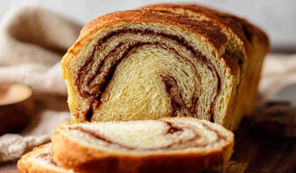 Homemade Cinnamon Swirl Bread sliced on a rustic wooden board