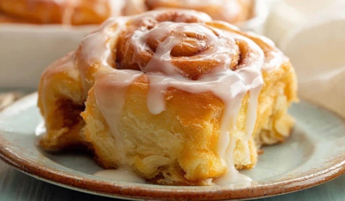 Homemade Orange Sweet Rolls stacked on a ceramic plate with dripping glaze