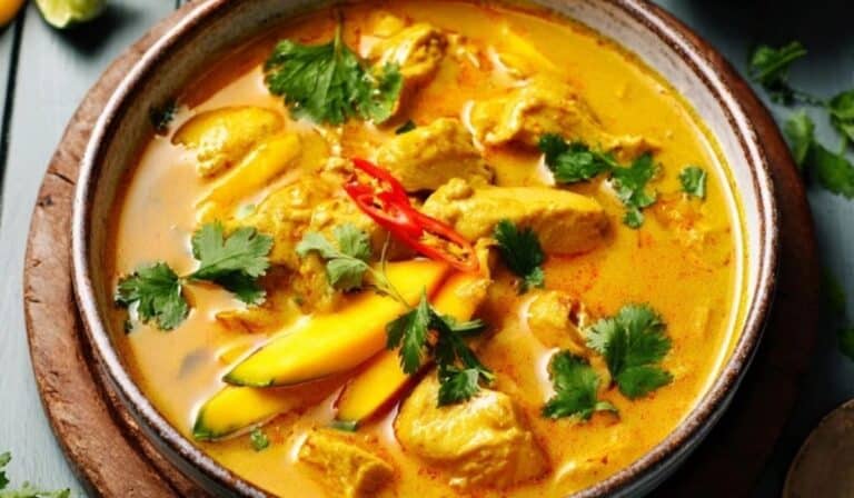 Mango chicken curry served in a rustic bowl with cilantro