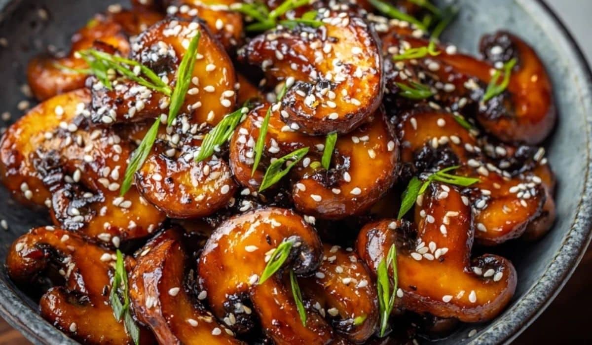 Gochujang Mushrooms served in a dark ceramic bowl with scallions and sesame seeds
