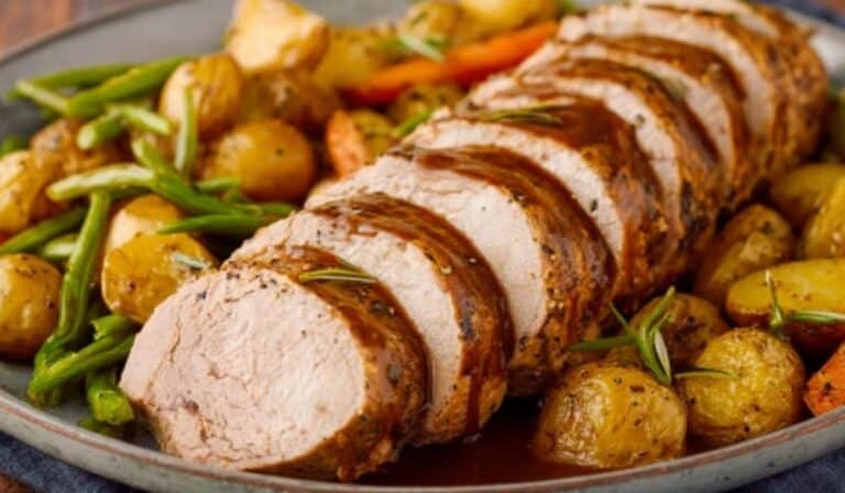 Perfect Pork Tenderloin sliced on platter with pan juices and roasted vegetables