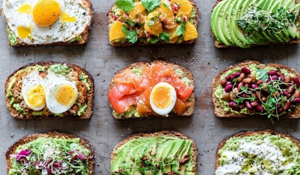 Avocado toast 10 ways on a wooden board with colorful toppings