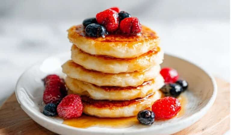 Fluffy cottage cheese pancakes stacked high with berries and maple syrup.