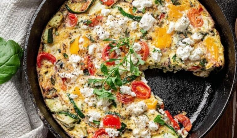 Egg white frittata with feta and spinach in a skillet on a wooden table