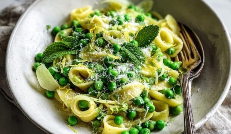 Pea and mint pasta side in a white bowl with lemon zest and Parmesan