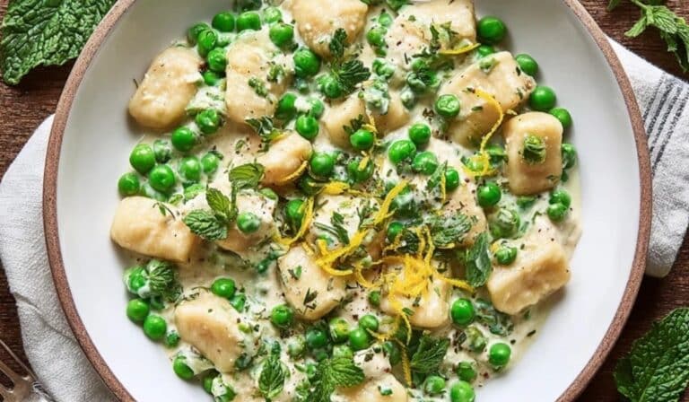 Spring gnocchi with peas and ricotta in a white bowl with lemon and herbs