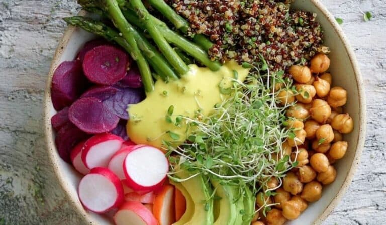 Vibrant spring Buddha bowl with quinoa, asparagus, peas, radishes, avocado, and chickpeas